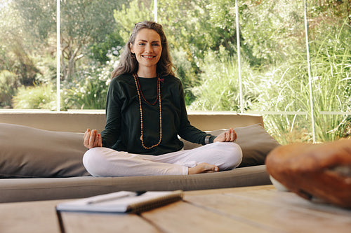Happy holistic healer meditating in her living room