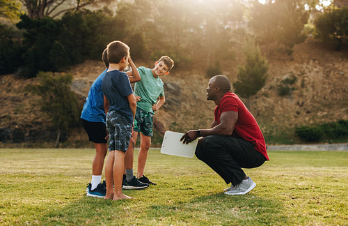 Coach having a team talk with children in a school ground