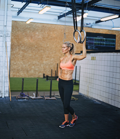 Muscular female athlete holding gymnast rings