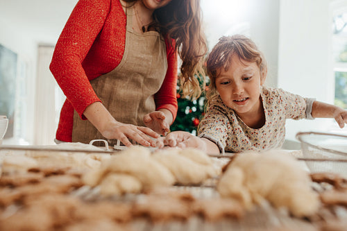 Little girl helping her mother in making cookies for  Christmas.