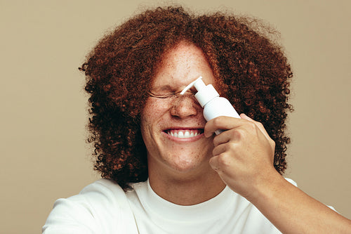 Excited young man holding facial serum for his skincare routine