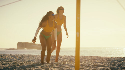 Slow-motion shot of female beach volleyball player throwing herself on the sand during sunset play