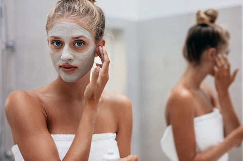 Woman applying facial mask in bathroom