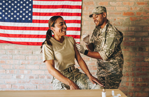 Cheerful servicewoman receiving a vaccine in the military hospit