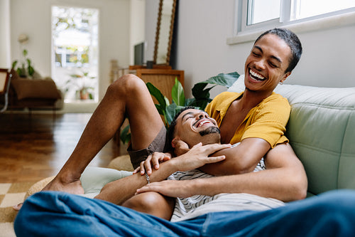 Happy gay couple laughing together on a couch at home