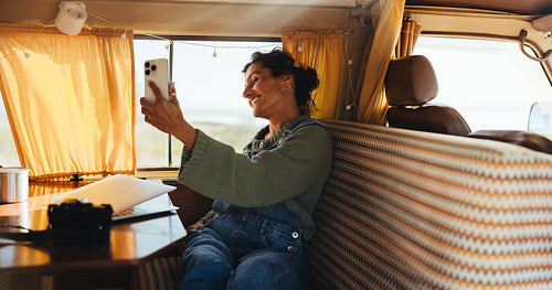 Woman in camper van taking a selfie, enjoying road trip and cozy van life