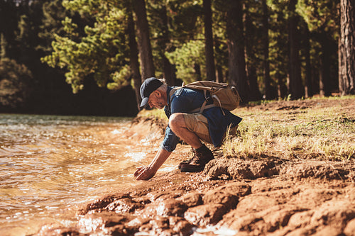 Mature male hiker washing face in lake