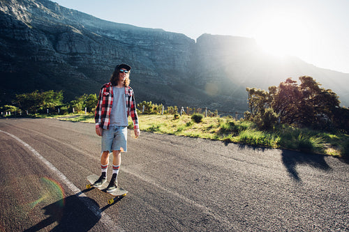 Young man longboarding outdoors on rural road