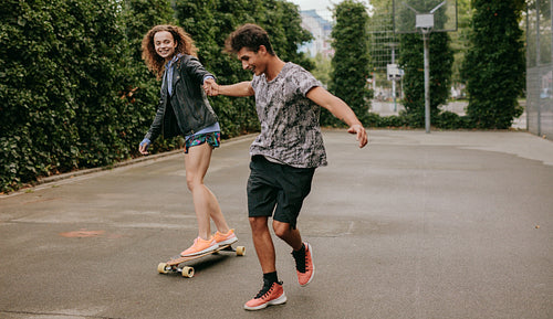 Woman skating on a basketball court with friend