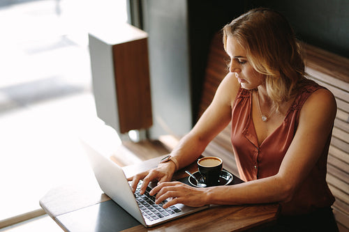 Woman working on a laptop computer at a coffee shop