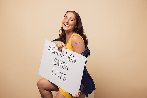 Woman holding a "Vaccination Saves Lives" banner