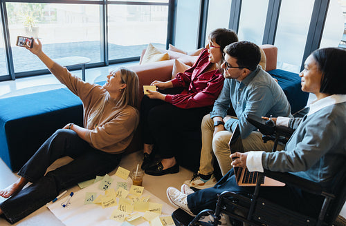 Group of professionals collaborating and taking selfie in modern office environment