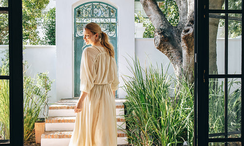 Smiling tourist woman standing in a stylish summer dress