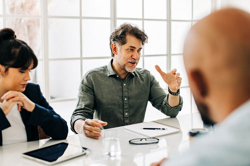 Senior man having a discussion with his team in an office