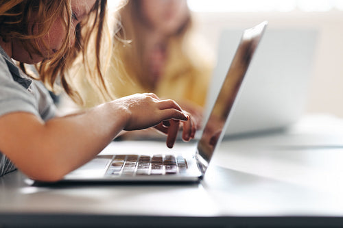 Young boy hitting the keyboard in a classroom, completing a digital literacy task