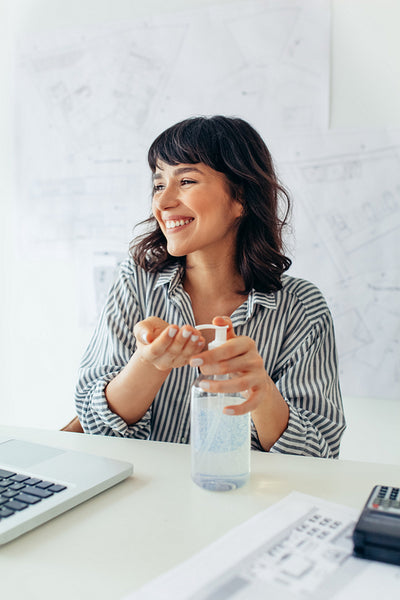 Businesswoman sanitizing her hands with sanitizer