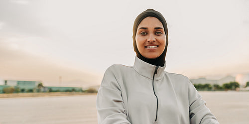 Sporty Muslim woman smiling at the camera outdoors