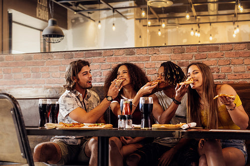 Crazy young friends enjoying eating pizza