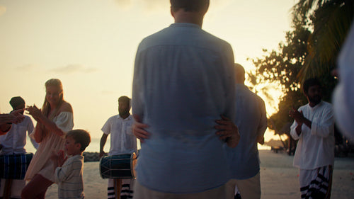 Family enjoying a beautiful sunset dance on a tropical island resort vacation