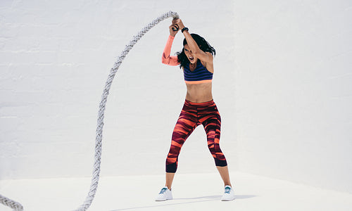 Fitness woman working hard on a battle rope