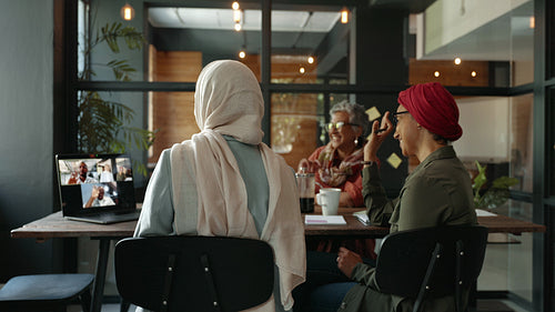 Online meeting in a coworking office: Remote team connects with their colleagues with a laptop