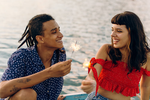 Romantic young couple celebrating with Bengal lights while on a