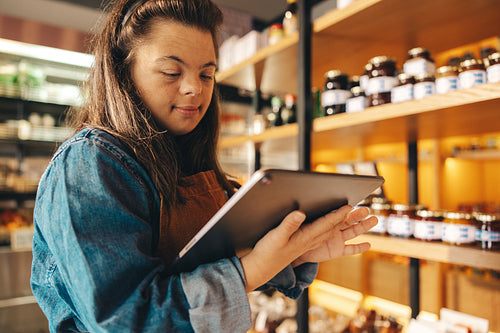 Store employee with Down syndrome taking stock using a digital tablet