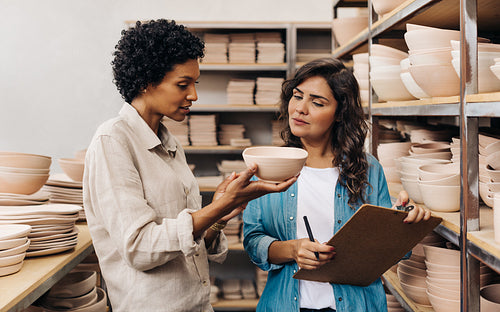 Female ceramists discussing one of their handmade products