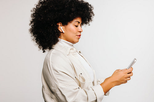 Young woman listening to music using a smartphone and earbuds