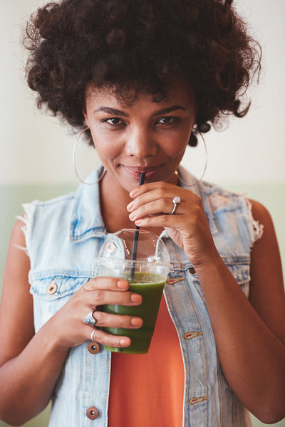 Attractive african woman drinking fresh fruit juice