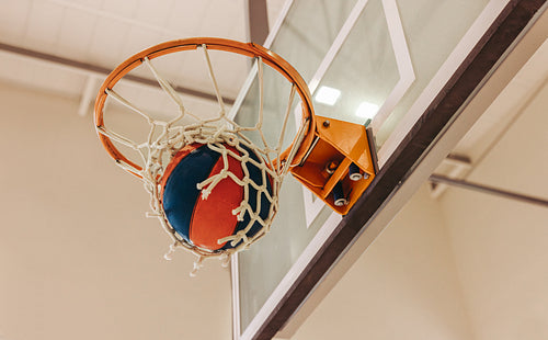Basketball scoring with ball inside hoop during an exciting indoor game