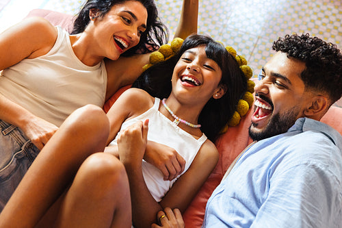 Happy Latino family laughing together while relaxing at home on a bright day