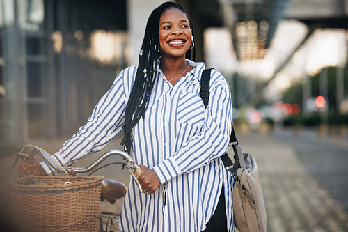 Excited young businesswoman pushing her bicycle on her way to work in the city