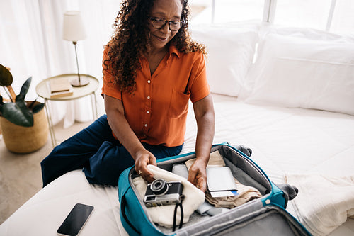 Mature tourist unpacking her carry-on luggage on a sightseeing trip
