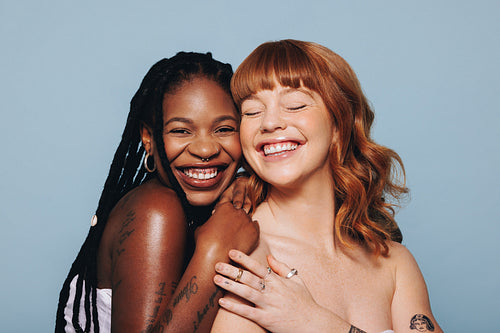 Cheerful young women with different skin tones smiling while standing together