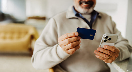 Senior man shops online with credit card and smartphone