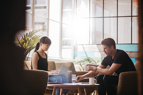 Two businesspeople meeting in lobby area of modern office