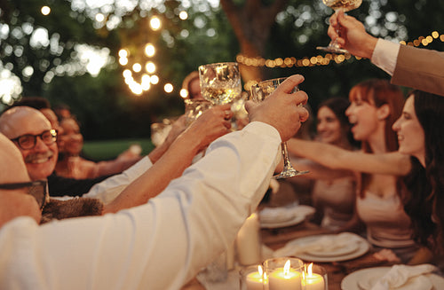 Celebration with friends toasting wine glasses outdoors under warm glowing lights
