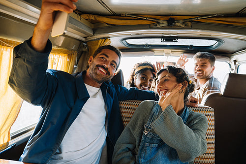 Friends take a group selfie inside a retro van during a joyful road trip