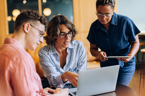 Team discussing work in a casual office setting on a laptop