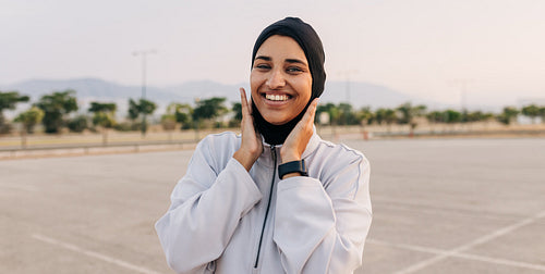 Happy Muslim woman standing outdoors in sportswear
