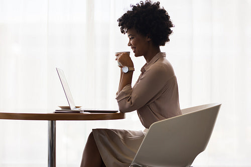 Smiling businesswoman drinking coffee and using laptop