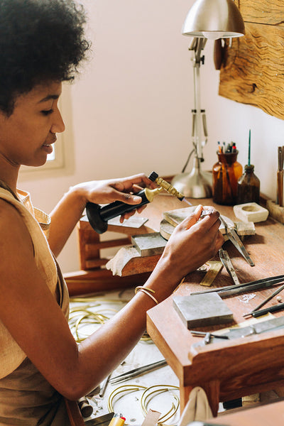 Jeweler making ornament at her desk in studio