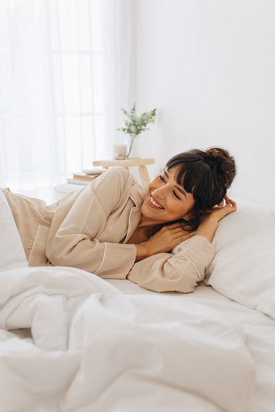 Smiling woman waking up from sleep lying on bed