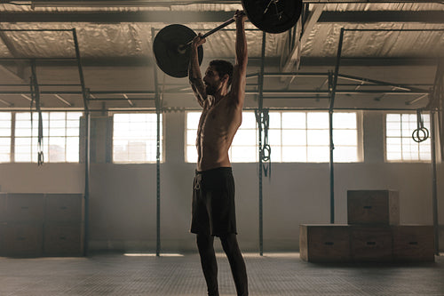 Muscular man exercising with barbell