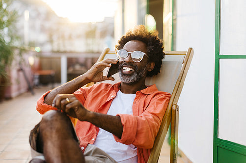 Mature black man enjoying a phone call outdoors on the patio