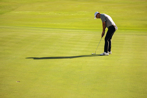 Golfer putting on a lush green golf course at a resort on a sunny day