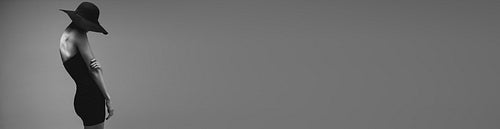 Sensual woman in black dress on wide grey background