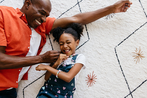 Laughing father and daughter playing together on the floor