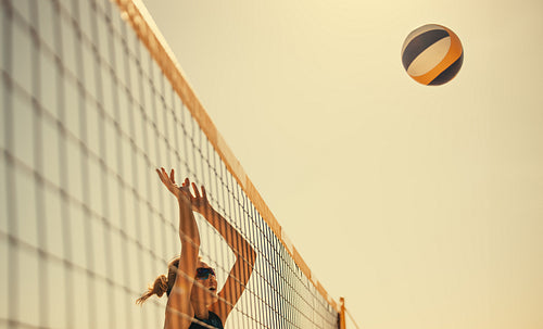 Happy female athlete spikes ball in mid-air during coastal beach volleyball championship